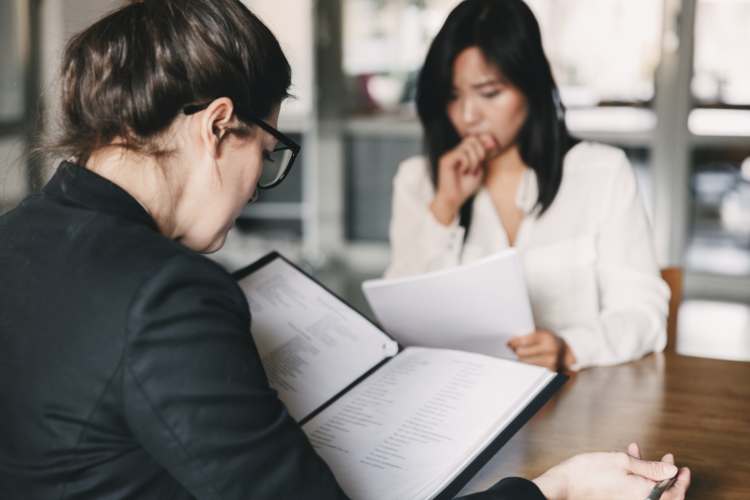 Two women reviewing documents at a table.